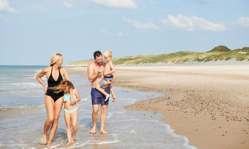 mann og kone med to barn på stranden ved hirtshals i danmark.