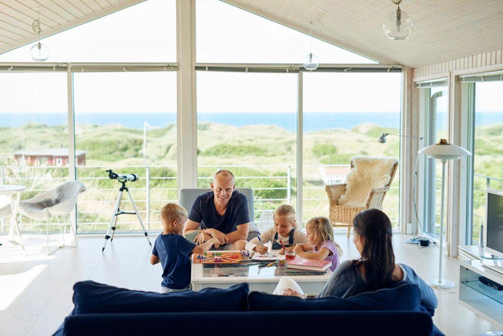 mann og kone med te små barn som er inne på en hytte i danmark nær sjøen. tegner og leker utsikt mot sjøen