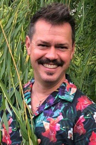 Bilde av Espen Skarphagen med stort smil og i i blomstrete skjorte i hagen sin.