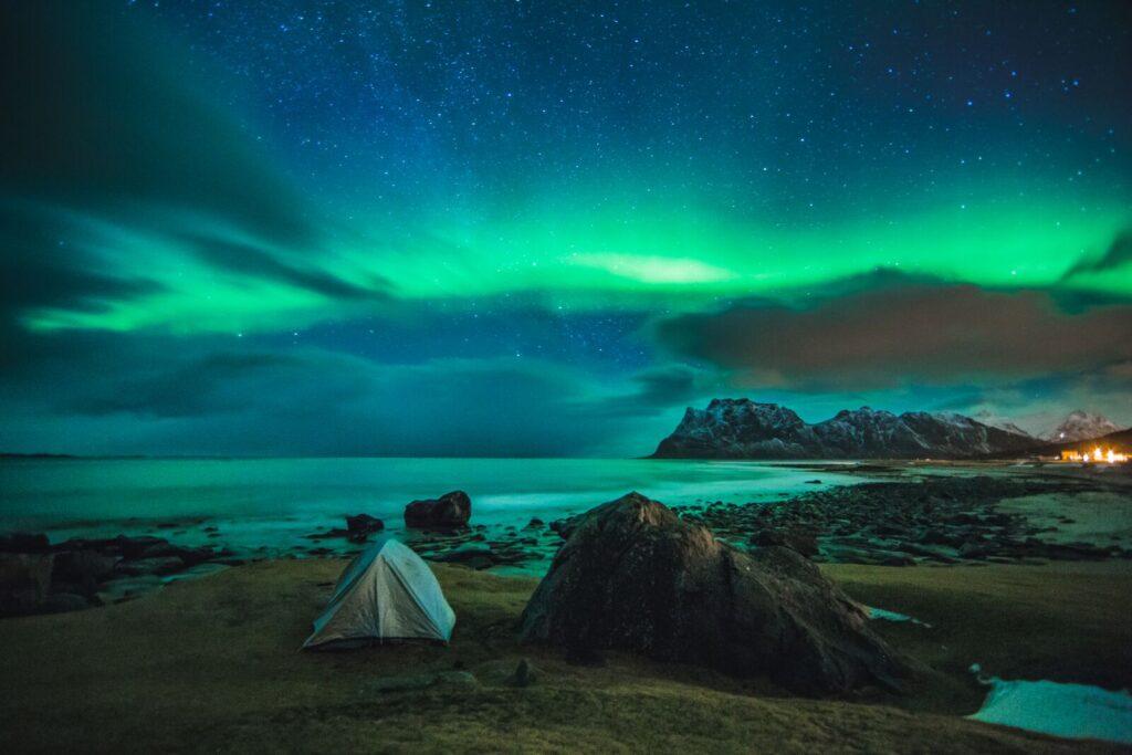 nordlys eller aurora borealis over uttakleiv strand i lofoten. telt i skråningen.