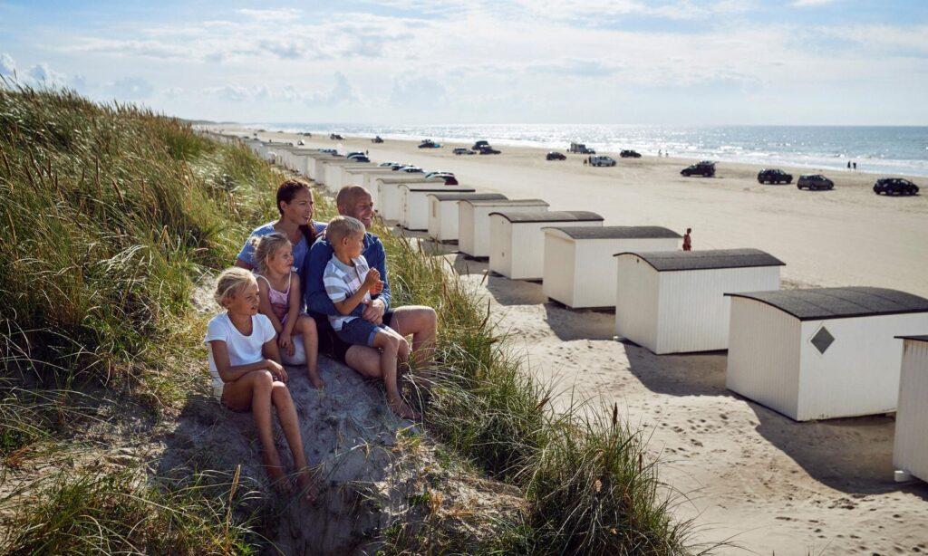 familie som speider utover stranden på løkken med utsikt til de hvite badehusene i den danske badebyen