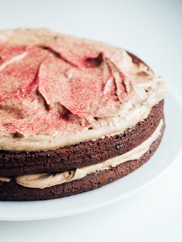 Vi deler oppskrift på avbildet saftig, vegansk sjokoladekake. Her på nærbilde med glasur og rosa dryss.