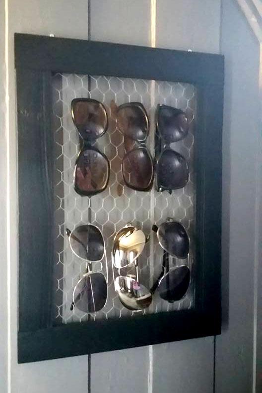 Bilde av smart DIY oppbevaring av solbriller hengede på hønsenetting inni ramme på veggen.