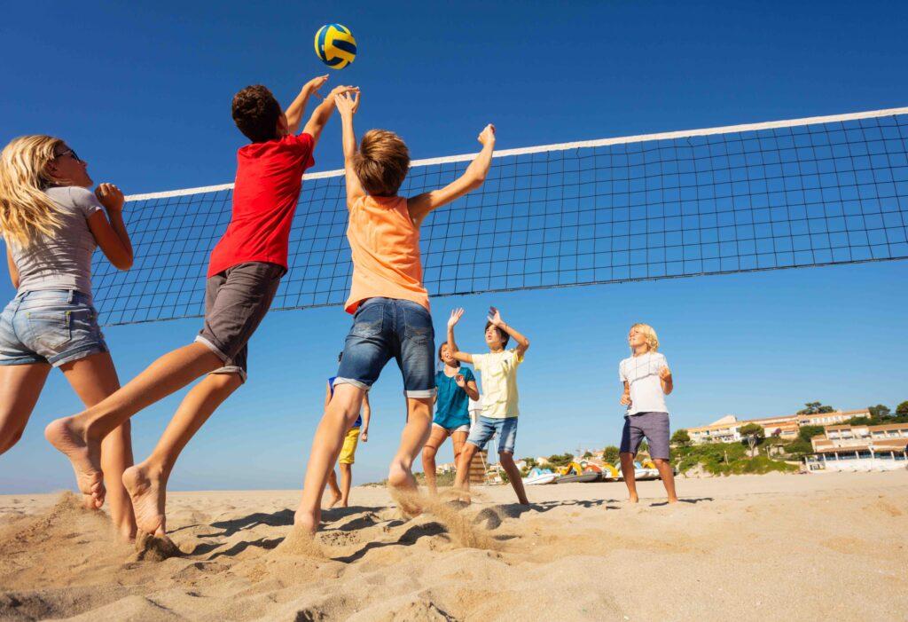 barn som spiler volleyball på stranden på sommeren er en fin aktivitet å gjøre i sommerferien