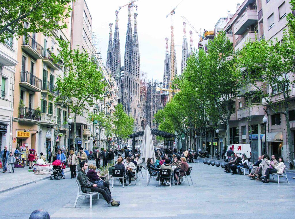 Barcelonas gater er fullt av yrende folkeliv. i bakgrunnen kan du skimte La Sagrada Familia.