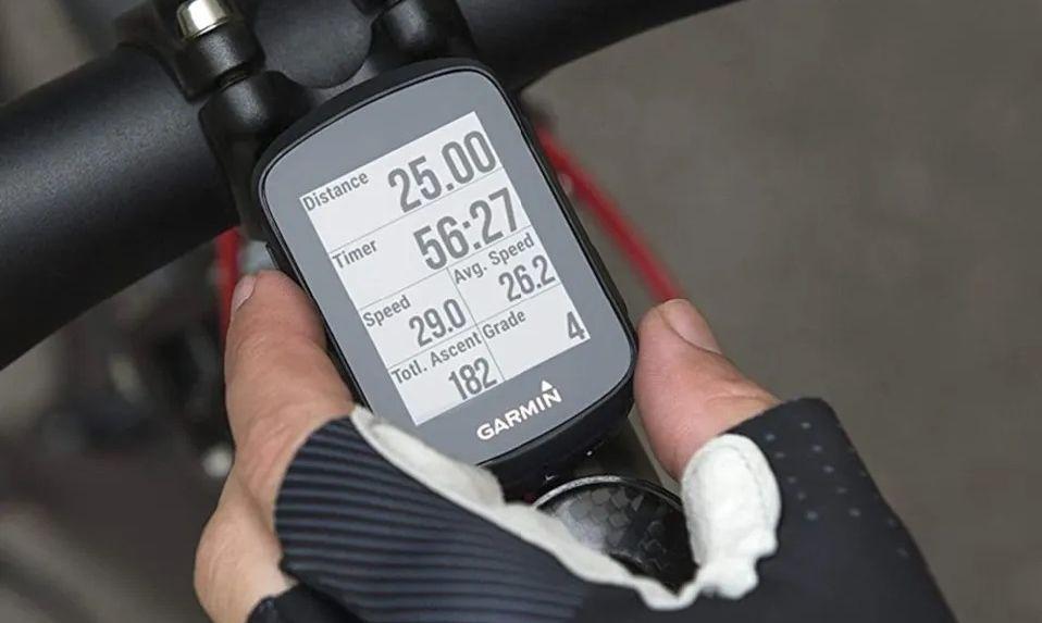 Bilde av hand med hansker som holder en GPS-klokke festet på sykkel.