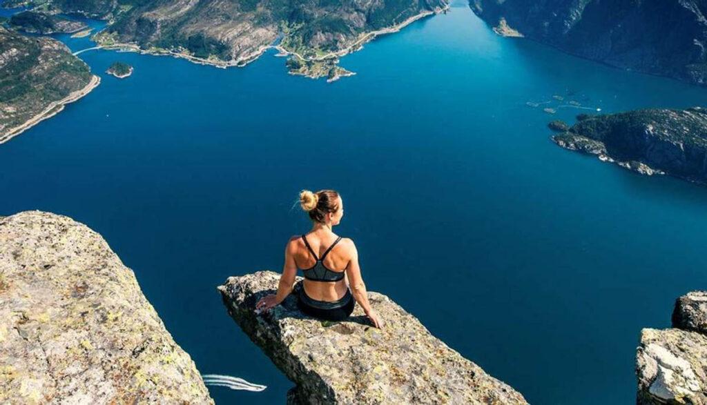 Kvinne på tuppen av Hornelen i Bremanger, Norge. En fjelltur med fantastisk utsikt over hav. 