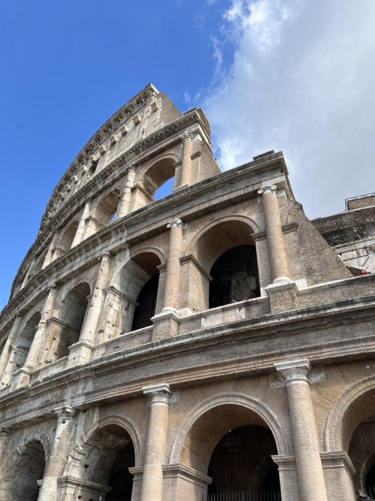 Bilde av toppen av Colosseum i Roma mot blå himmel. Listen over ting man bør gjøre i Roma er lang, men vi har samlet fem ting som vi mener er et must-see for en historieentusiast. På listen finner du: Colosseum, Forum Romanum, Domus Aurea, Vatikanstaten og Pantheon.