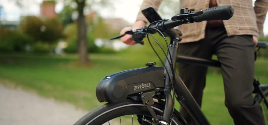 Bilde av person med sort sykkel med el-motoren som gjør din vanlige sykkel om til elsykkel på 1-2-3: Zip Force.