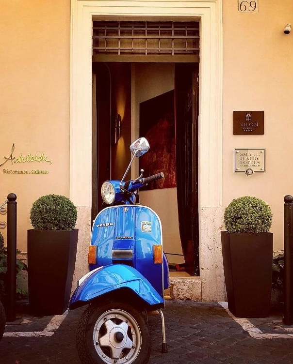 Blå scooter utenfor hotellinngang i Roma i Italia.