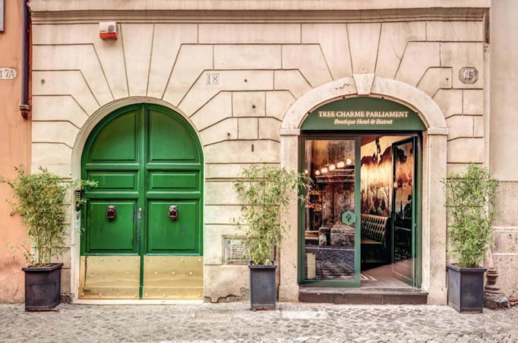 Inngangsparti på hotell i Roma med grønn dør og grønne planter rundt 