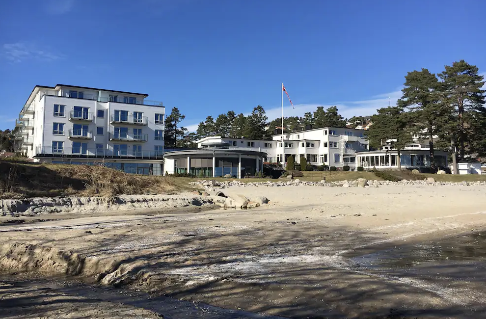 Strand Hotel Fevik er et stort hvitt hotell som ligger på stranden.