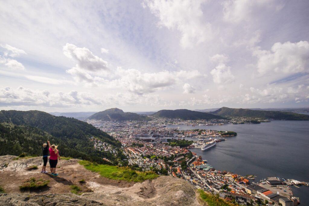 Bilde av to personer som har gått fjelltur til toppen av Stoltzen i Bergen. Fantastisk utsikt over Bergen i bakgrunn. En av våre anbefalte fjellturer i Norge.