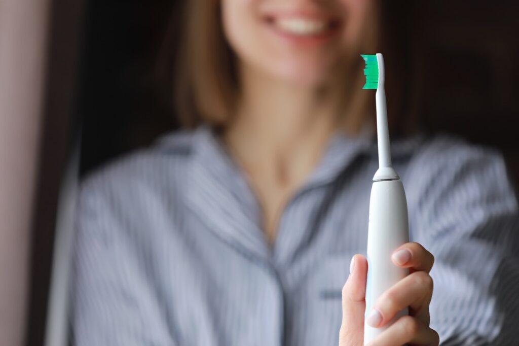 Bilde av smilende kvinne med elektrisk tannbørste:  Vi har funnet frem de elektriske tannbørstene som er best i test.