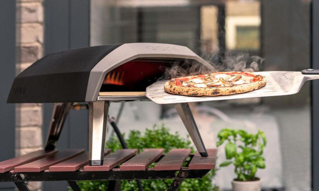 Best i test pizzaovn: Pizzaspade med pizza på ut av pizzaovn.