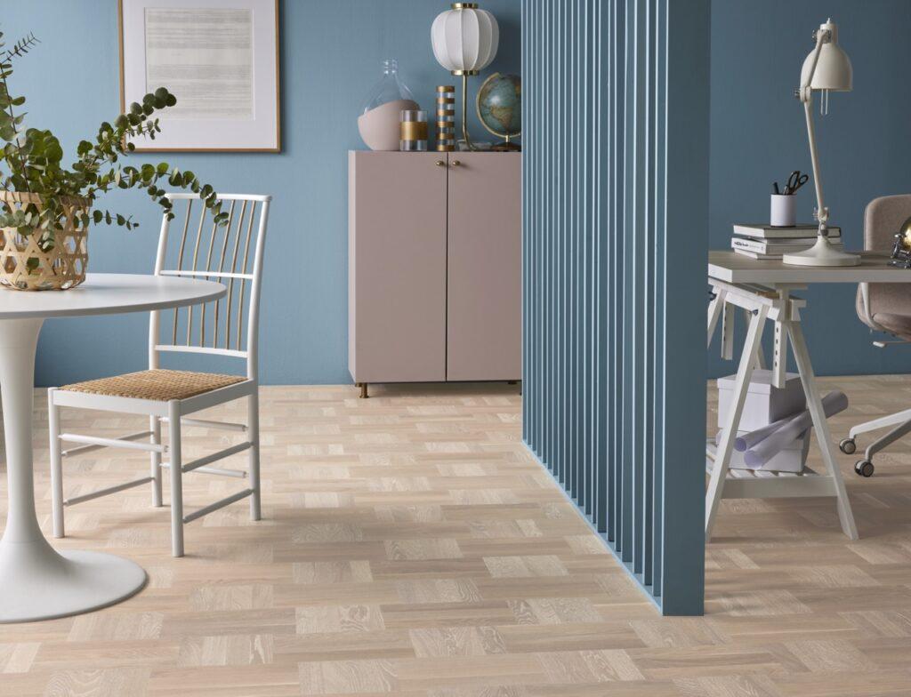 Hvordan vaske gulv? Bilde av parkett i et rom med skillevegg og vegger i blå, hvite spisemøbler og vakker innredning.