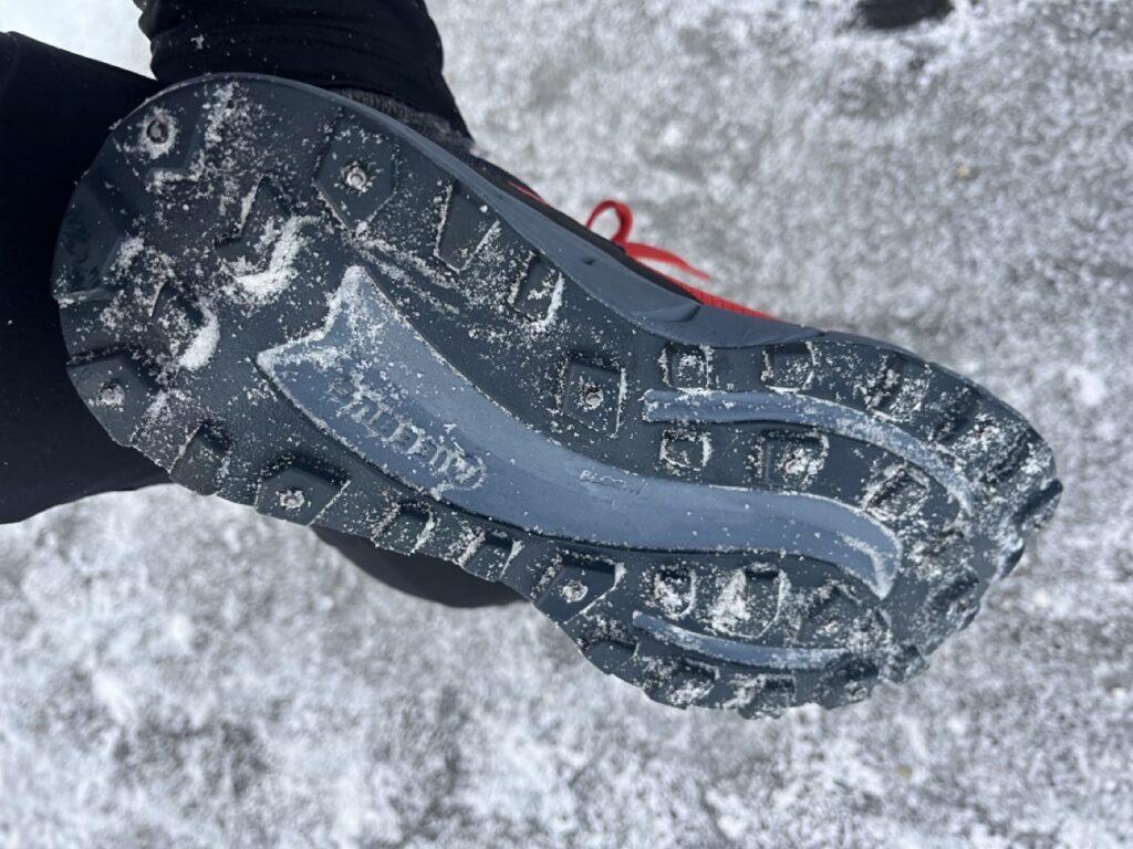 Bilde av undersiden av piggsko til dame ute i snø og is. Vi har funnet piggskoene som er best i test til dame, og avbildede sko er fra Icebug i modellen Icebug Arcus Bugrip.