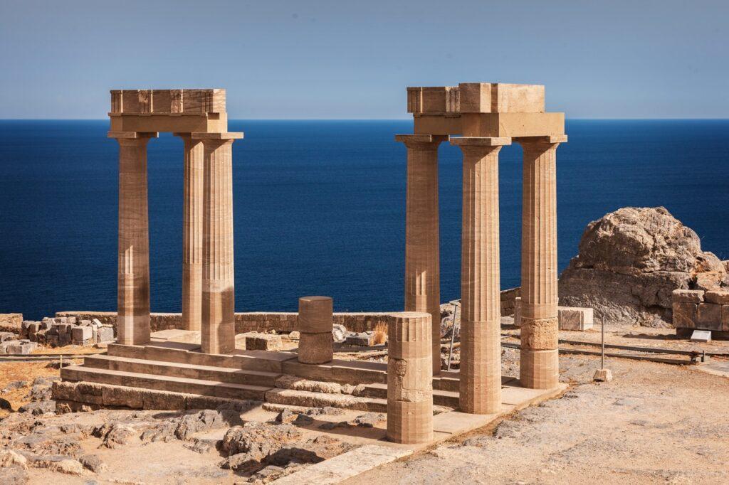 Bilde av akropolis på Lindos som ligger på øya Rhodos i Hellas. I bakgrunnen ser du blått hav så langt øyet kan se. Rhodos i Hellas er en drøm, og her får du både billige reiser og pakkereiser til den greske øya. Vi gir deg også fem ting du må se og gjøre på Rhodos, samt svar på ofte stilte spørsmål om øya.