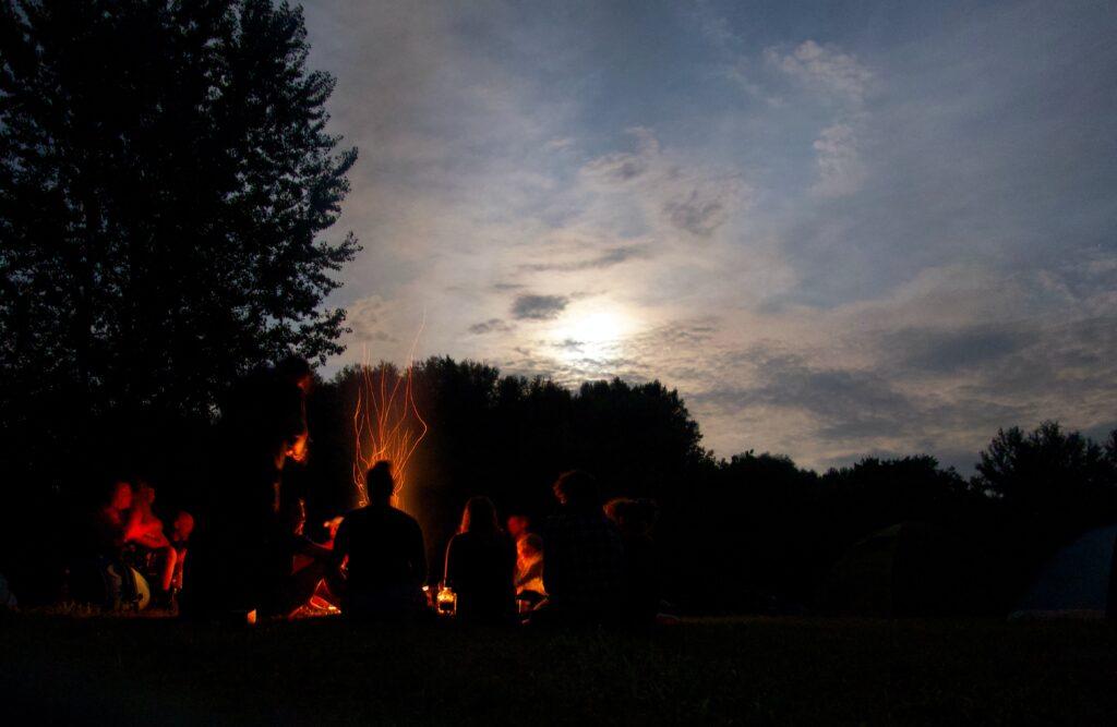 Rentbrennende bålpanne: En gruppe mennesker sitter rundt et bål på nattestid. 