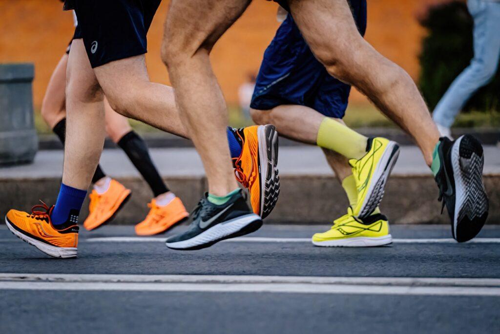 Bilde av løpere med forskjellige løpesko på seg. På bildet ser du føtter med joggesko fra Nike, Asics og Saucony fra et løp. Vi firteller hvorfor Nike’s Zoom Vaporfly 4% ble vurdert forbudt og avslører hvilke sko fra New Balance , Adidas og Asics som er forbudt.