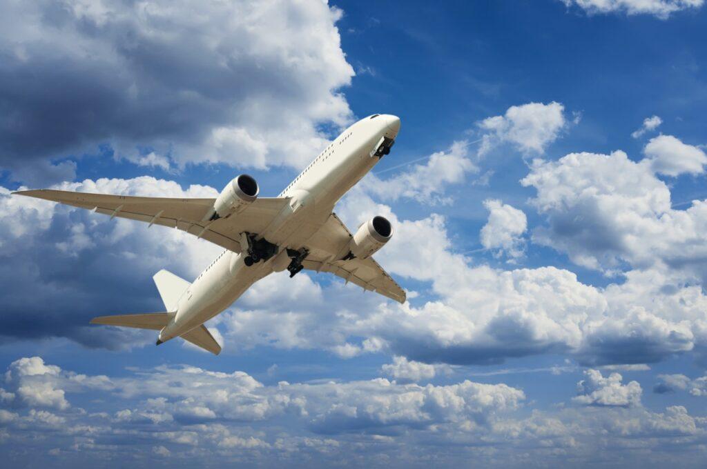 Bilde av et fly som flyr blandt skyer og blå himmel. Er flybilletter billigere nærmere avreise?