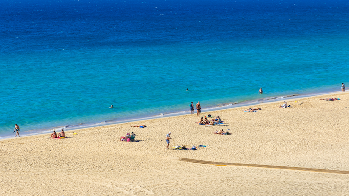 Bilde av hvit strand og blått hav. Fuerteventura er en ferieperle i sen spanske øygruppa kanariøyene. restplass til Fuerteventura er en fin måte å spare penger på ferie på.