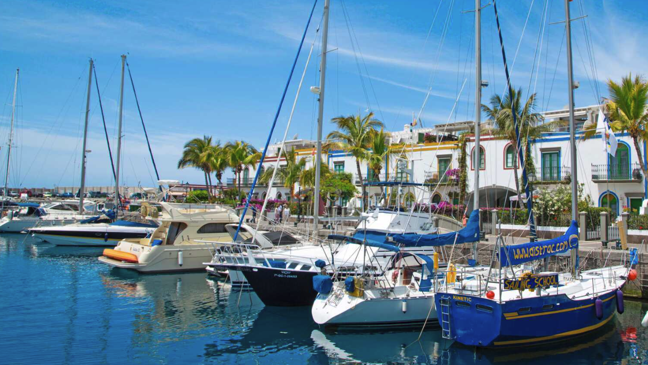 Bilde av båter i havn på Gran Canaria, med sol og blå himmel. Vi forteller hvordan du kan sikre deg billige restplasser til Gran Canaria. Nå kan du sikre deg en billig reise med restplass til gran canaria. Restplasser til Gran Canaria kan være en fin måte å finne en billig reise til varmere strøk. Vi har samlet billige restplasser i 2023 på både hotell og fly.  
