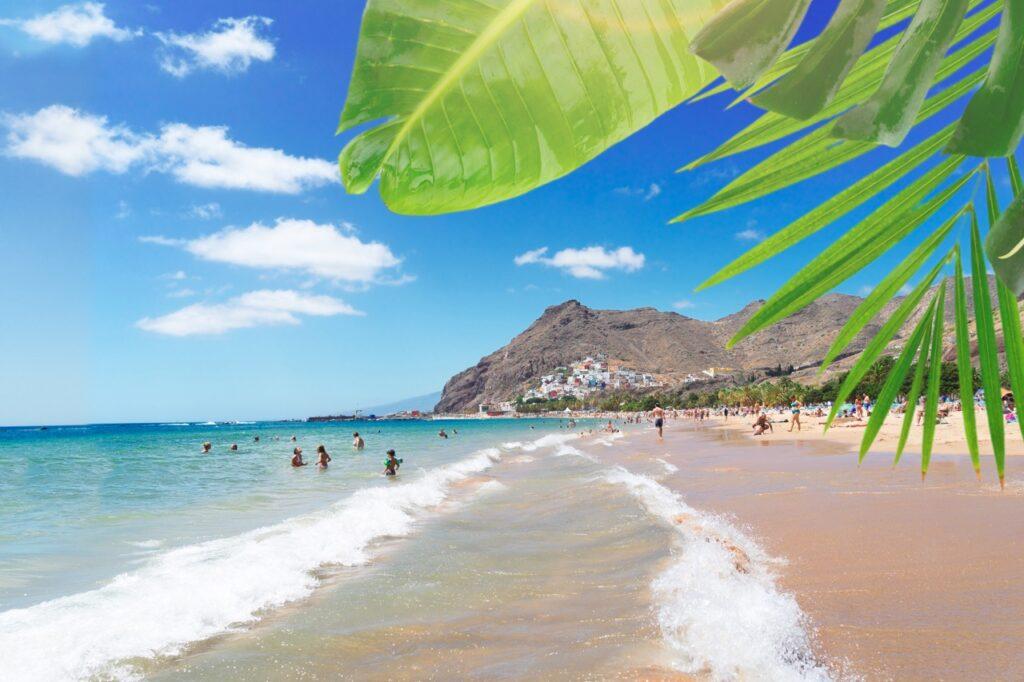 Bilde av en strand på Tenerife, du ser blått hav og flere som koser seg i varmen. Ute etter billig reise? Da bør du sjekke ut Apollos Black Week-salg. Her får du billige reiser til steder som Gran Canaria, Tenerife og flere.