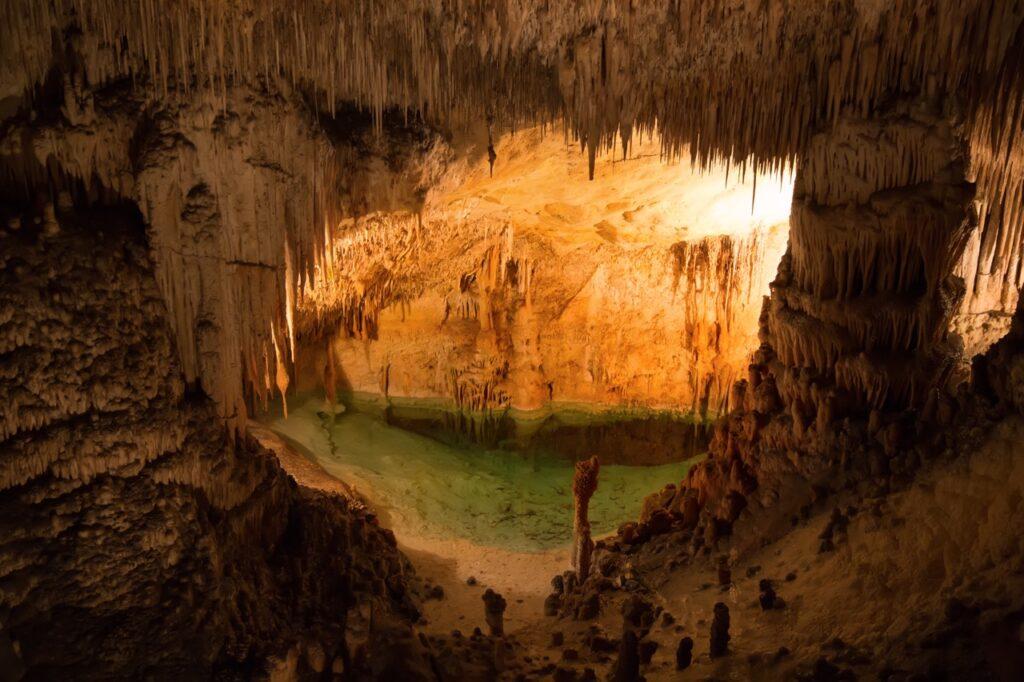 Cuevas del Drach, også kalt dragegrottene på Mallorca. Her ser du den opplyste grotten hvor det henger istapplingnede formasjoner fra taket. I bunnen av grotten kan du se et klart vann.