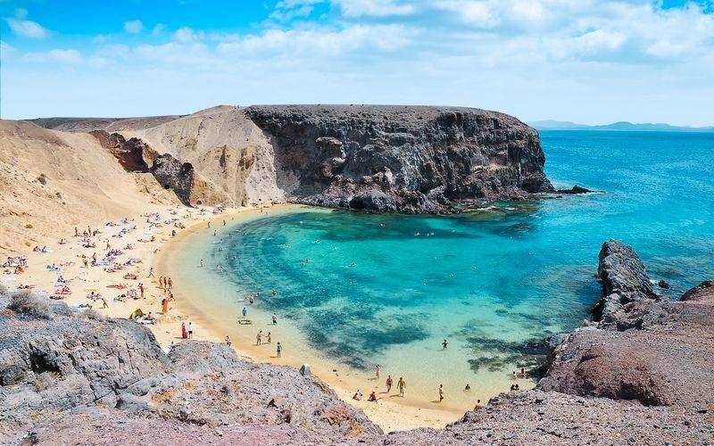 Bilde av en strend på Lanzarote med knallblått hav og lavastein rundt. Vi har snakket med redaktør i Lanzaroteposten, Ola Kjeldstad som gir oss sine beste tips til en topp 5 Lanzarote-guide.