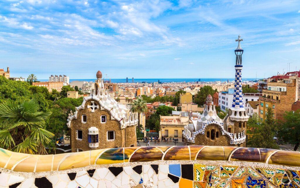 Bilde av et utsiktspunkt i Barcelona hvor man ser byen i bakgrunnen og blått hav. Himmelen er blå med noen skyer. Her finner du billige storbyferier i Europa til byer som London, Berlin, Barcelona, Paris og Roma.
