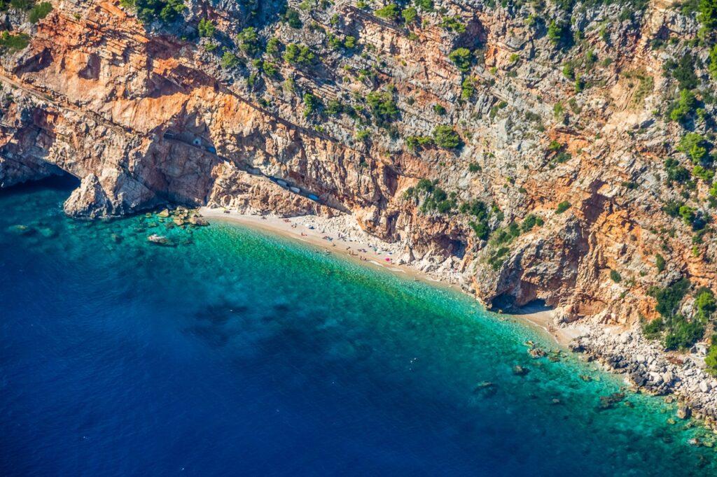 Pasjača-stranden som ligger i nærheten til Dubrovnik i Kroatia. Her ser du en avsidesliggende strand omringet av høye klipper og krystallklart hav. Dubrovnik byr på alt fra vakre strender til historiske severdigheter som Fort Lovrijenac, som også har blitt brukt som sett i den populære serien Game of Thrones.