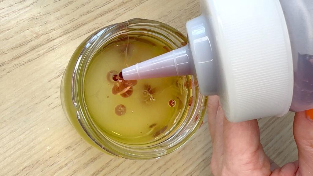 Fruktjuice som dryppes i et glass med olje for å lage fruktkaviar.