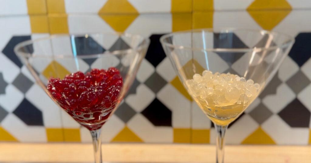 Røde og gule fruktbobler i hvert sitt cocktailglass. Vi viser hvordan du lager fruktkaviar.