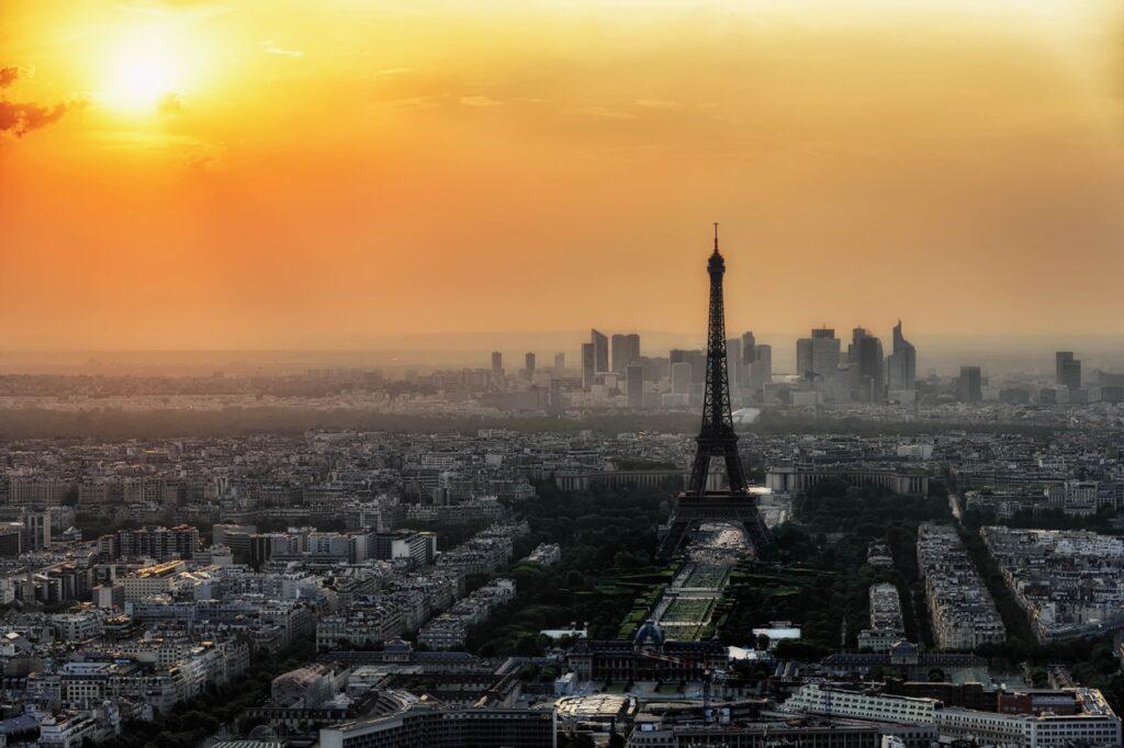 utsiktsbilde av Paris hvor du ser Eiffeltårnet stå i sentrum. Det er solnedgang og himmelen er orange. Bilde er tatt fra Montparnasse som gir god utsikt over byren. Eiffeltårnet, Triumfbuen, Louvre, Champs-Élysées og Notre Dame er alle severdigheter de fleste av oss allerede assosierer med Paris. Byen som også kalles «kjærlighetens by» kan by på mye mer en de klassiske turistfellene (som absolutt burde oppleves!), og vi har derfor samlet ti skjulte skatter du finner i Paris.
