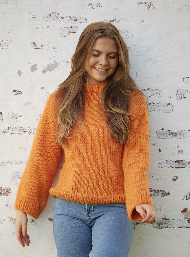 Jente med oransje genser. Strikkegenser for nybegynnere. Foto: Gry Traaen