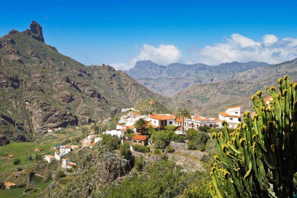 Utsiktsbilde fra Tejeda på Gran Canaria. På bildet ser du en liten landsby omringet av grønne busker, og i bakgrunnen ser du et høyt fjell. Her får du en guide til Kanariøya fra noen som har bodd der i mange år og som skriver for Canariajournalen.