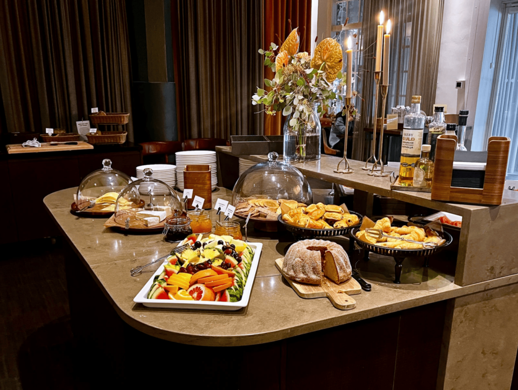 Fargerikt frokostbord med ulike typer frukt, bakverk og oster.