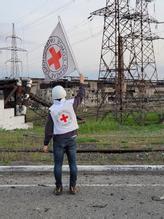 En representant for Røde Kors vifter med et flagg utenfor stålverket. Foto: Røde Kors / AP / NTB
