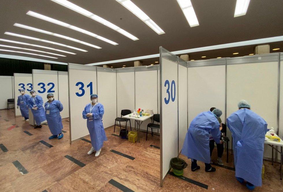 A man receives a Pfizer-BioNTech's Comirnaty COVID-19 vaccine as medical staff wait for patients at the “Sala Palatului” event hall in Bucharest, Romania on May 07, 2021, as Bucharest’s authorities start a vaccination marathon during the weekend. (Photo by Daniel MIHAILESCU / AFP)
