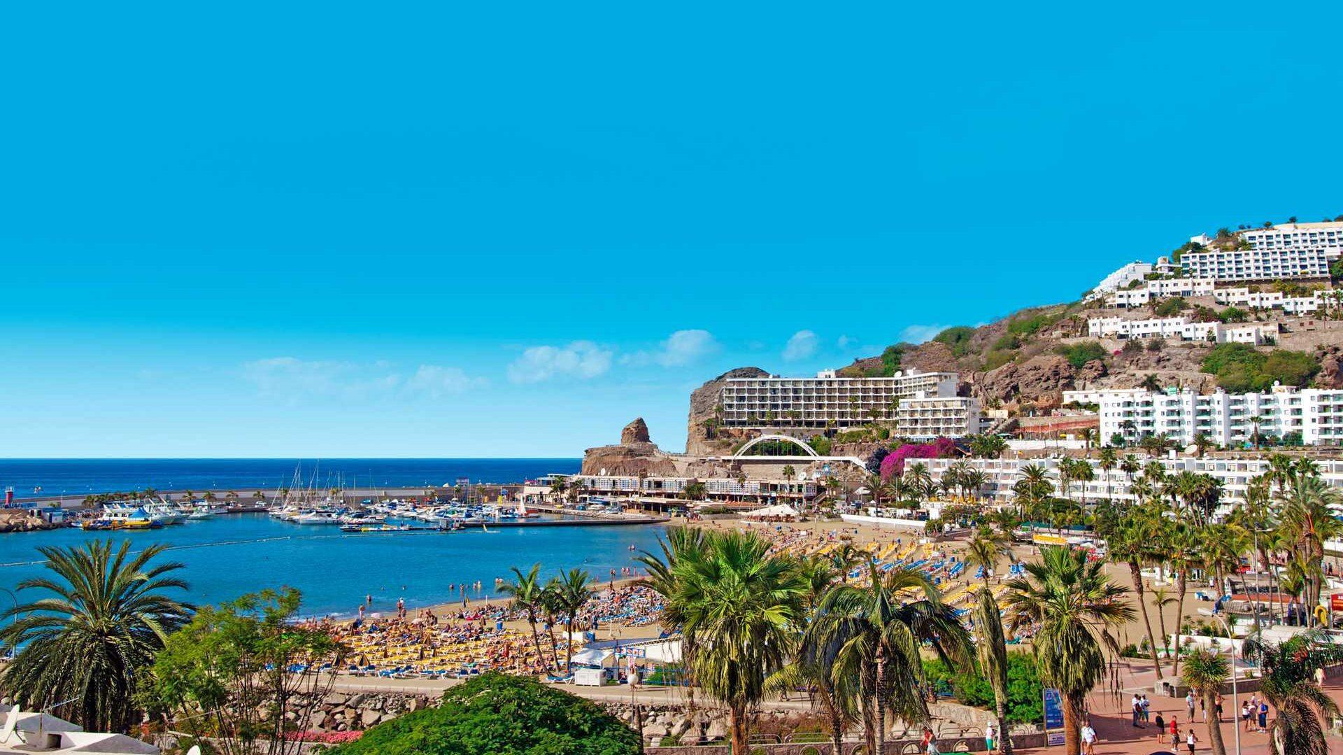 Bilde av Puerto Rico Gran Canaria - Dette er stedet nordmenn helst vil bo på ferieøya. på bilde ser vu landskapet med hoteller, solsenger, strand og krystallblått hav.
